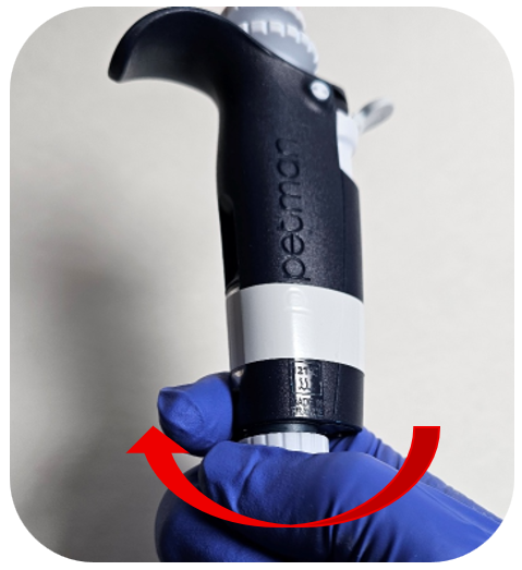 A gloved hand removes the connecting nut of a Pipetman pipette, with a red arrow indicating the direction to turn the nut.
